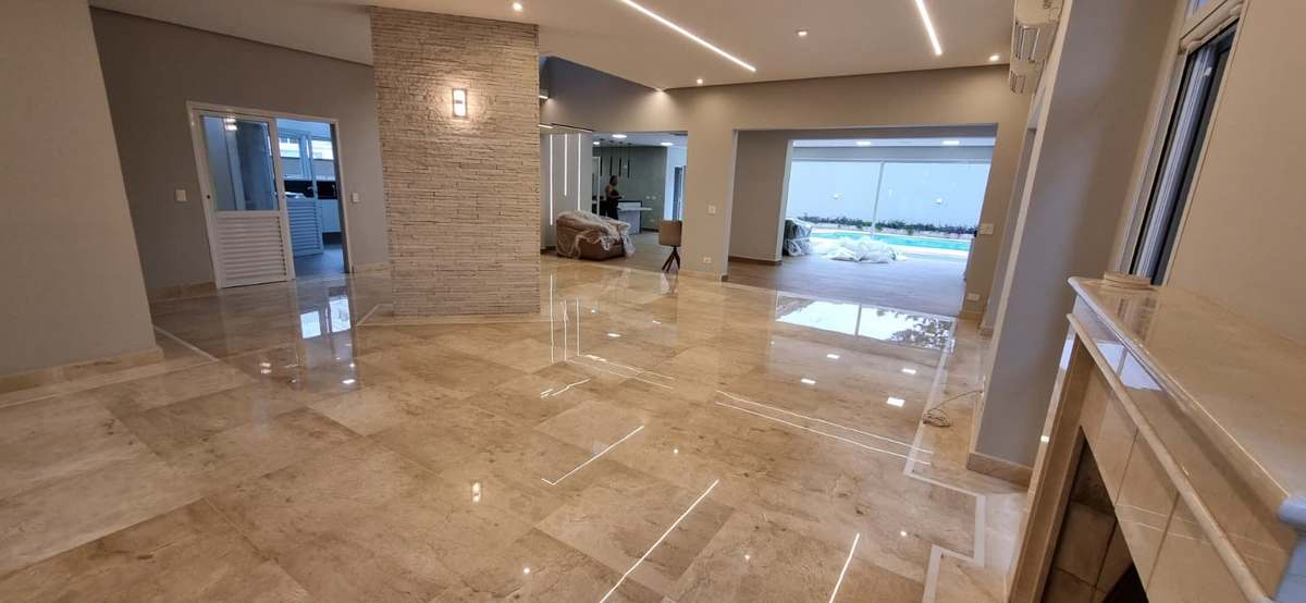 Salão residencial com piso de mármore espelhado e vista para a piscina